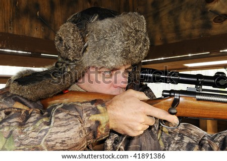 Profile view of man sighting rifle