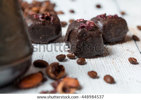 handmade chocolates without heat treatment lie on an old wooden table with cracked paint on the surface. raw food diet concept. coffee cocoa beans grated cinnamon. rustic style