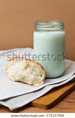 Still life with Fresh bread and milk. A piece of bread and glass jar of fresh milk