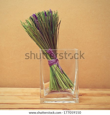 Bouquet of dried lavender flowers in a glass vase on wooden table. Dry Lavender