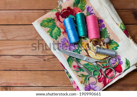 Background with sewing tools and colored thread. Sewing accessories. Scissors, bobbins with thread and needles on wooden table