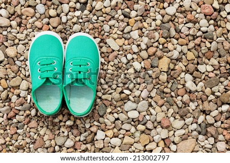 Green sneakers on a background of small stones. Pair of shoes