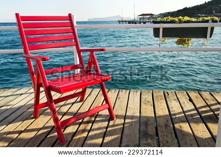 Red beach chair. Red beach chair on a pier over the sea