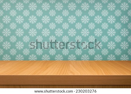 Empty wooden table over vintage wallpaper with a pattern of snowflakes. Ready for product montage display. Holiday background