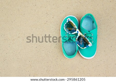 Green sneakers and sunglasses. Summer holidays. Top view trendy shoes and glasses. Hipster set. Children theme. Space for text