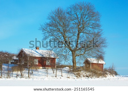 HOLO, SWEDEN, FEBRUARY 06 2015. A little older red cottage in rural setting, photographed a winter day with snow and cold.