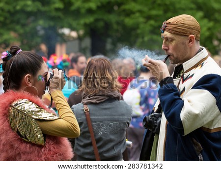 STOCKHOLM, SWEDEN - MAY 31, 2015. Peace and Love Parade. Street party in Stockholm. Woman photographing a smoking man.