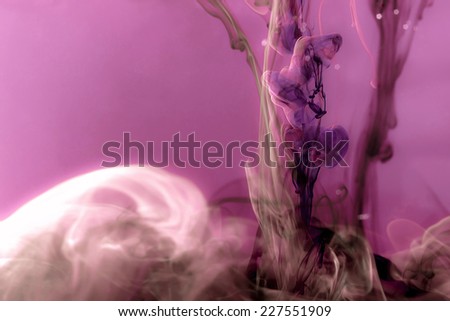Colors dropped into liquid and photographed while in motion. Ink swirling in water. Cloud of silky ink in water on pink background. Colorful pink and violet ink in water, an abstract banner.