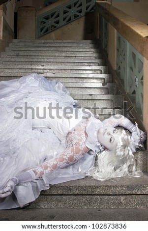 Beautiful princess all in white with a little crown laying on the stairs