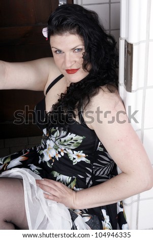 Pretty woman wearing a summer dress posing in a changing room of a public bath