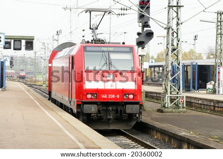 German red commuter train entering station