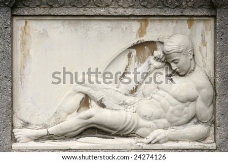 Ancient male sculpture at a gravestone in a grave yard