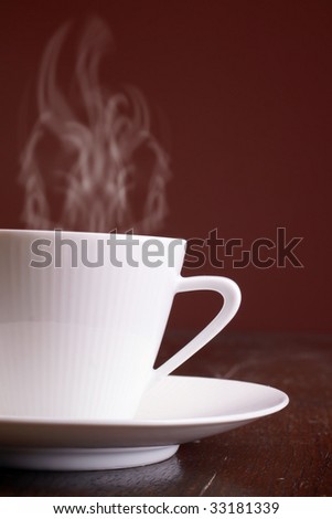 Cup of steaming hot coffee over dark background.