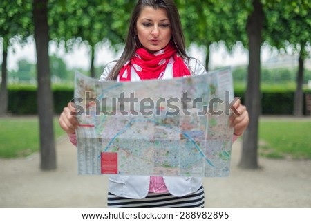 Confused young girl holding city Maps in Tuileries garden Paris, France