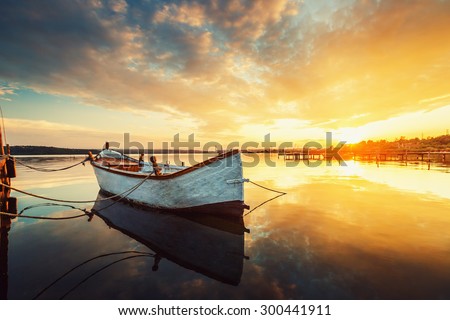 Boat on lake with a reflection in the water at sunset
