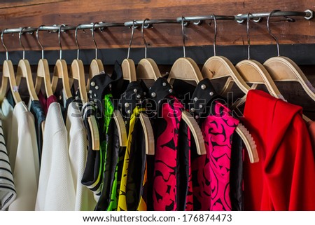 Many blouses on hangers in the dressing room.