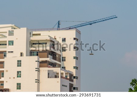 man standing on iron bars held up by mega crane.