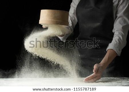 An experienced chef in a professional kitchen prepares the dough with flour to make Italian Italian pasta. concept of nature, Italy, food, diet and biology. on a dark background