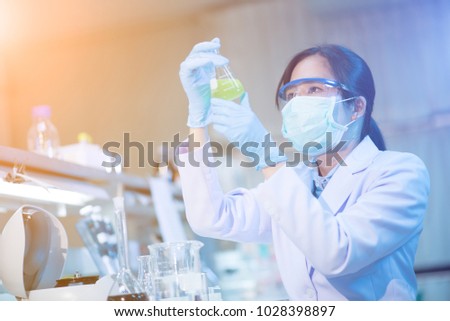 Young female scientist looking at the flask in medical laboratory. Researcher concept.