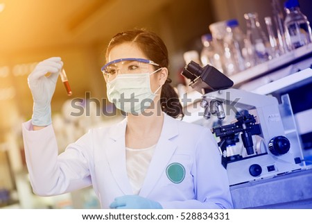 Young Asian researcher looking at the glass tube in the science laboratory.