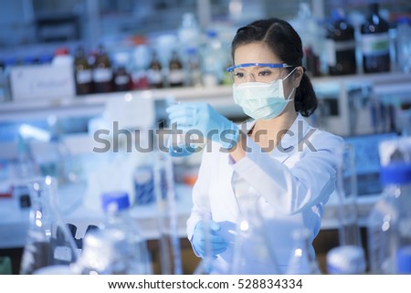 Young Asian researcher looking at the flask in the science laboratory.