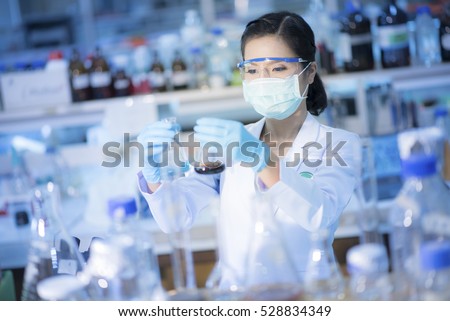 Young Asian researcher looking at the flask in the science laboratory.