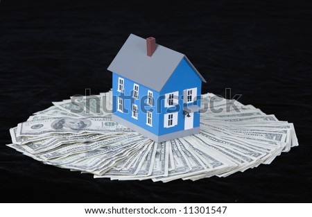 miniature house standing in the middle of a spread of US paper currency