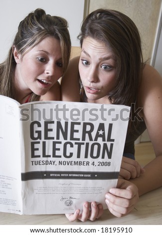 two teen-age girls reading the General Election guidelines to get ready to vote
