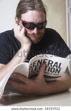 young man with dark glasses reading the General Election guidelines to figure out how to vote