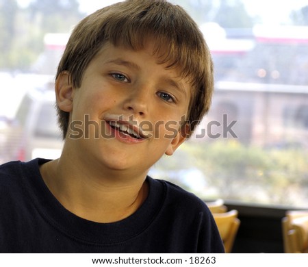 boy in a fast food restaurant with milkshake mustache on his upper lip