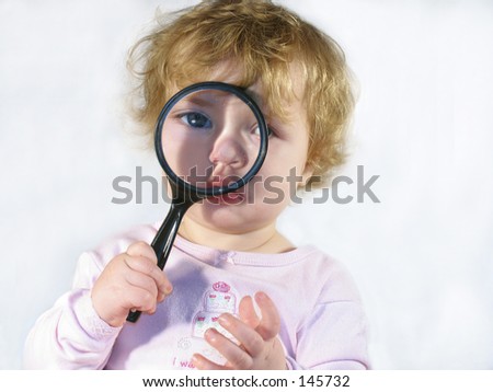 Toddler holding magnifying glass to eye on white background
