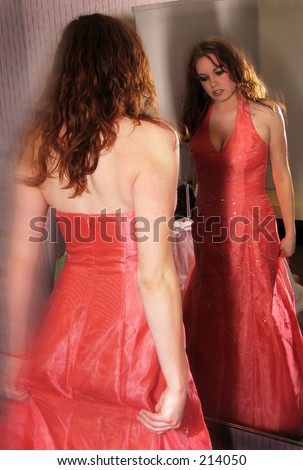 Girl trying on prom dress and looking in mirror
