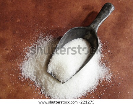 scoop of sugar on brown textured background