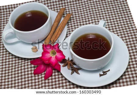 Two teacups with cinnamon and some pink flowers during an afternoon tea