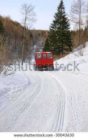 A red snow vehicle moving on the snow path