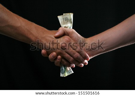 Handshake given with money in the middle as a form of bribery.