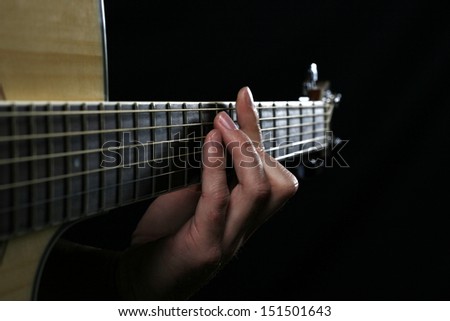 Close up of a man\'s hand on the fret board of a guitar.