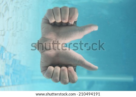 A hand showing thumbs up under water with a perfect refection showing that all is good.