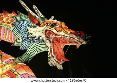 Fierce dragon face paper sculpture shining in the dark at a Asian lantern festival.