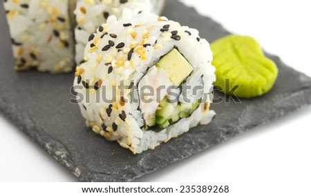 Sushi roll with esame on a stone plate isolated on white background