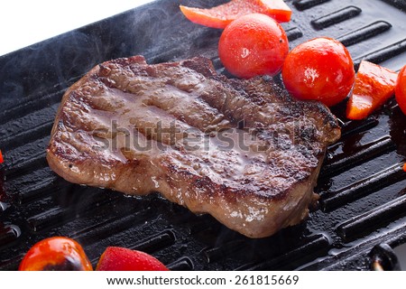 Stake with cherry tomato on a hot grill