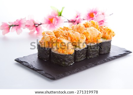 Spicy sushi roll on a stone plate over white background
