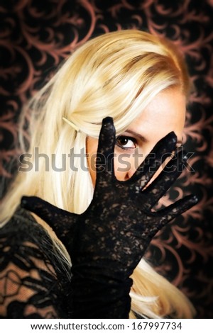 Elegantly dressed light hair model,looking through her fingers.