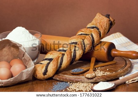 Sweet crispy pastry with poppy seeds, wheat seeds, flour and eggs, on a wooden table.