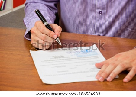 Close up of a male\'s hand, signing document.