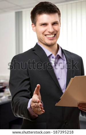 Positive young business man,greeting client inside his office.