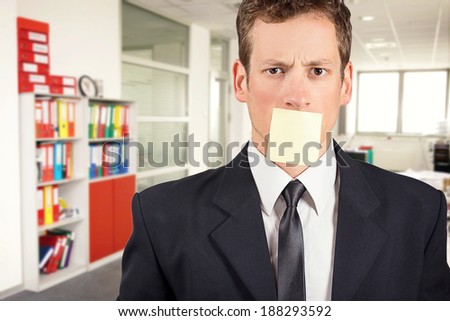 Young businessman with blank note on his mouth, inside office.