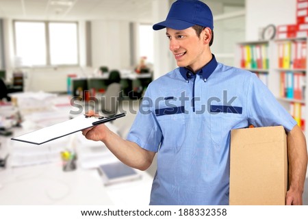 Smiling delivery man, holding clip board and carton box, inside office.