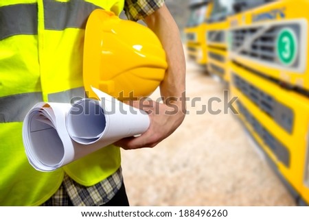 Close up of a construction worker\'s hand holding project documents and hat.