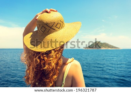Young curly woman, wearing hat, looking at horizon.